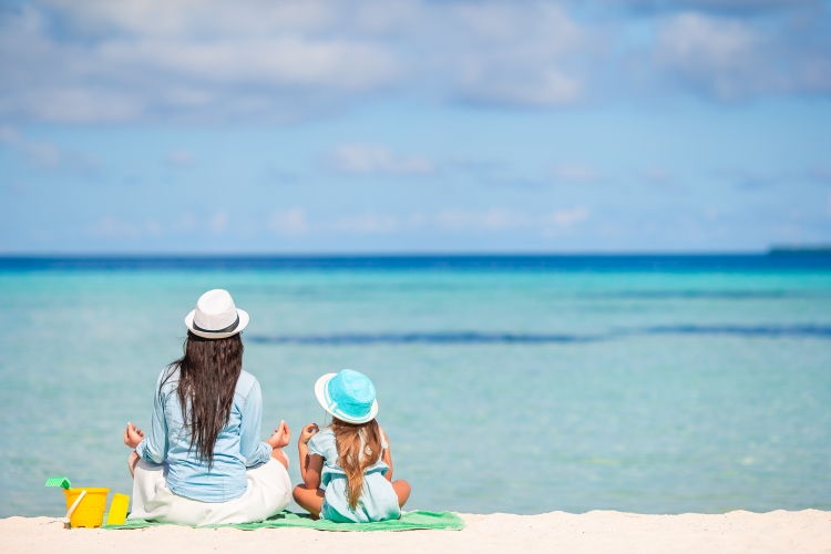 Mère et enfant méditant sur la plage pendant les vacances d'été