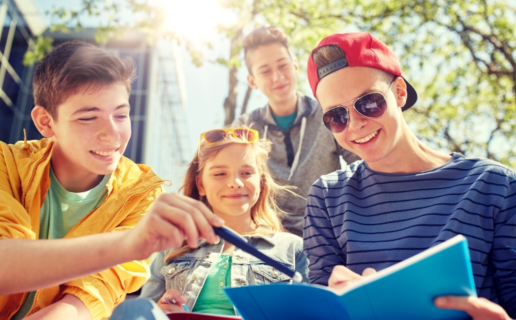 Groupe d'adolescents souriants étudiant en plein air pendant les vacances d'été