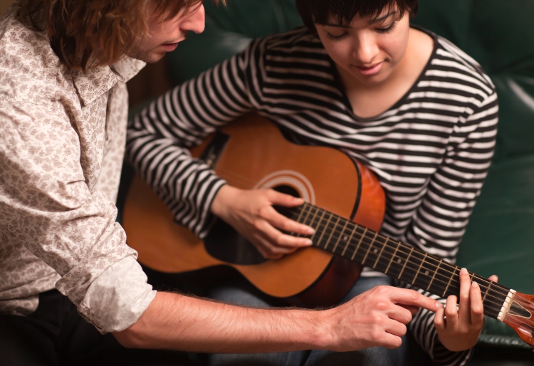 professeur de guitare donnant des conseils à une élève  lors d'un cours particulier