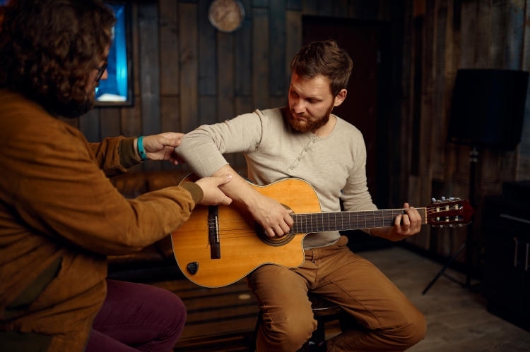 Professeur de guitare corrigeant un élève lors d'un cours particulier